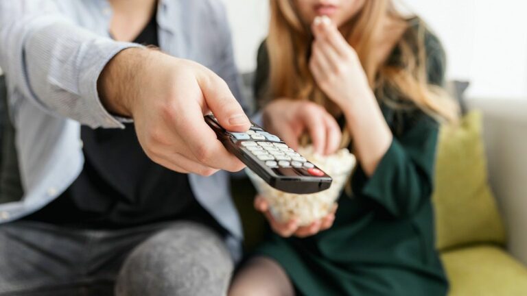 couple watching tv pointing remote controller